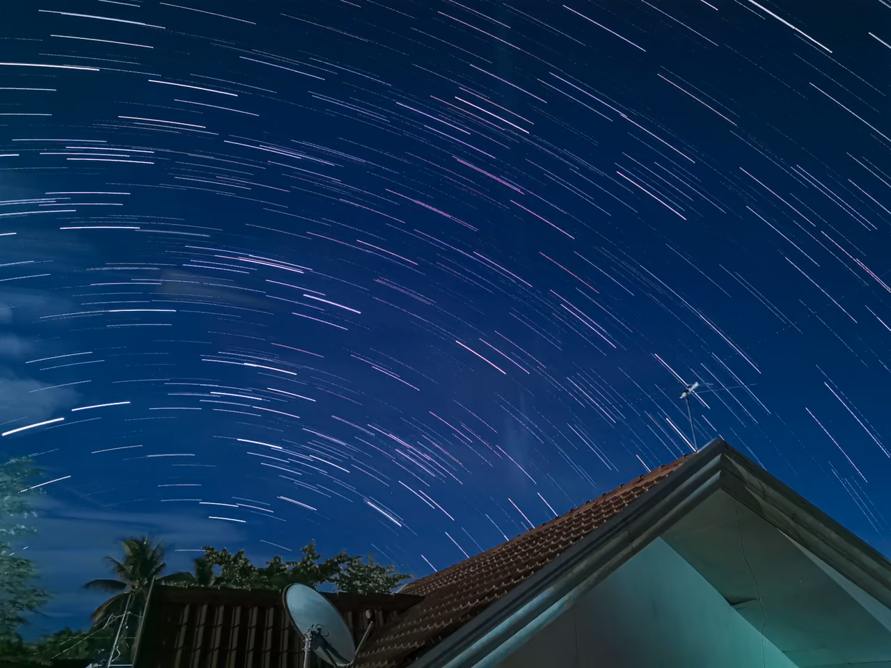 Stunning star trails photograph over a roof in Tagum City, displaying a vibrant night sky.